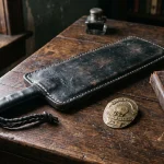 Vintage leather slap jack impact tool with brass police badge on rustic desk